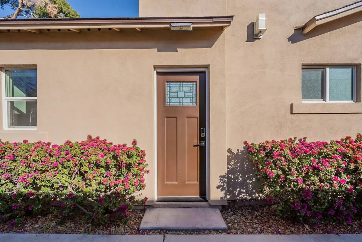 A friendly view of the front door framed by flowering bushes, suggesting a warm welcome to guests and the ease of coming and going. The front entry is clean and accessible, suitable for a business traveler’s quick transitions.